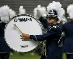 a man in uniform holding a drum and wearing a marching band hat with the words yamaha on it