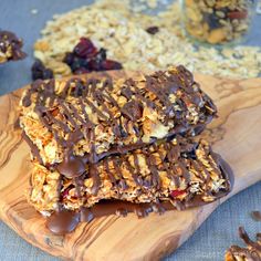 granola bars with chocolate drizzle and nuts on a wooden board next to other treats