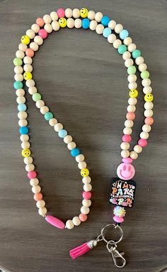 a white beaded lanyard with smiley face charms and a pink pacifier charm