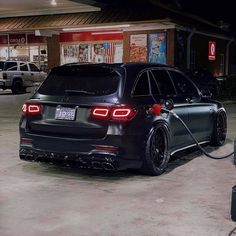 a black car parked in front of a gas station with nozzles on it