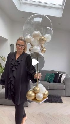 a woman standing in a living room holding balloons