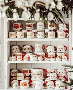 a shelf filled with lots of white and red christmas mugs on top of each other