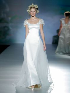 a woman in a white dress walking down a runway