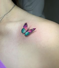 a pink and blue butterfly tattoo on the back of a woman's chest,