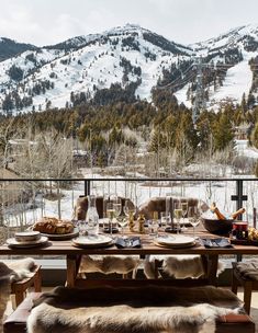 an outdoor dining table set for two with mountains in the background and snow on the ground