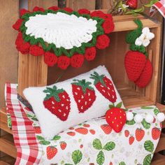 crocheted strawberries and strawberrys are displayed on a bench with red checkered tablecloth