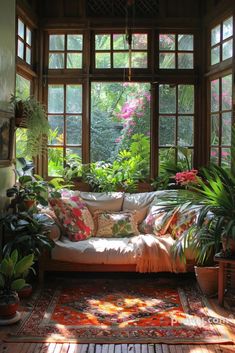 a living room filled with lots of plants next to a large window covered in sunlight