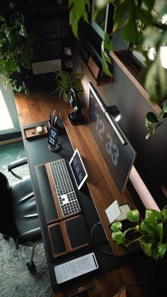 a desk with a laptop, monitor and keyboard on top of it next to a potted plant