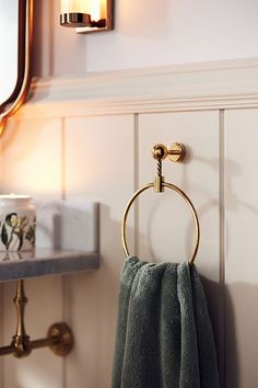 a towel rack in the corner of a bathroom with a mirror and light above it