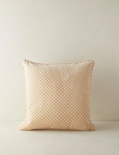 a beige and white checkered pillow sitting on top of a table