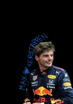 a man sitting in front of a black background wearing a red bull racing car uniform