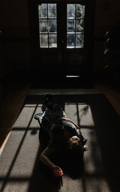 a woman laying on the floor in front of a window