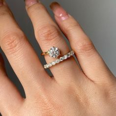 a woman's hand with two wedding rings on top of her ring and the middle finger