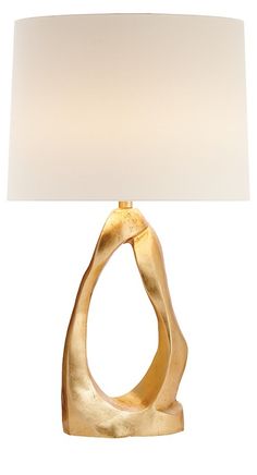 a gold lamp with a white shade on it's base and a light bulb in the shape of an object