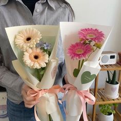 the man is holding two bouquets of flowers in his hands, both wrapped in paper and tied with ribbon