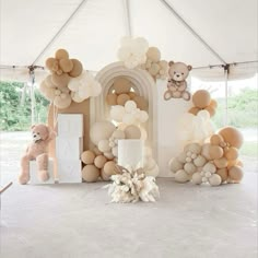 balloons and teddy bears are set up in front of a white tent for a baby's first birthday party