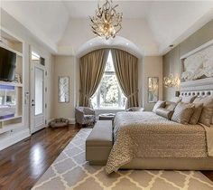 a bedroom with a large bed and a chandelier hanging from it's ceiling