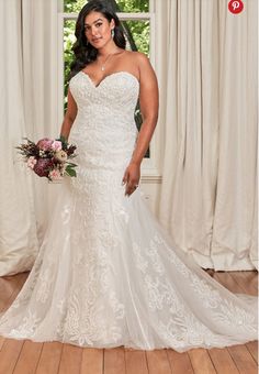 a woman standing in front of a window wearing a wedding dress