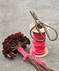 a spool of thread next to a flower and scissors on the ground with flowers