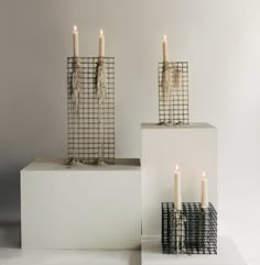 three candles sitting on top of white blocks