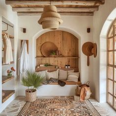 a room that has some plants and pillows on the floor in front of an arched window