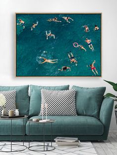 an aerial view of people swimming in the ocean on their surfboards, framed above a blue couch