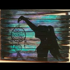 the silhouette of a woman holding a dream catcher on a wooden pallet with blue and purple background