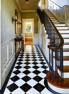 a black and white checkered floor in a house with stairs leading up to the second floor