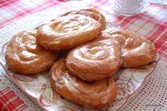 a plate full of glazed donuts on top of a red and white checkered table cloth