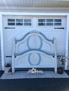 a bed sitting in front of a garage door with flowers on the ground next to it