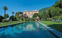 an outdoor swimming pool in front of a large house