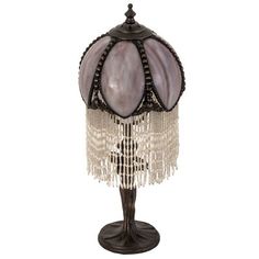 a lamp that is sitting on top of a stand with beads hanging from it's sides