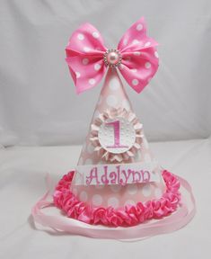 a pink and white polka dot birthday hat with the number 1 on it's side