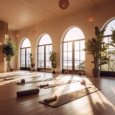 there are many yoga mats on the floor in front of large windows and potted plants