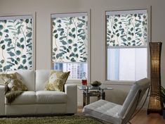 a living room filled with furniture and two windows covered in shades of green leaves on the blinds