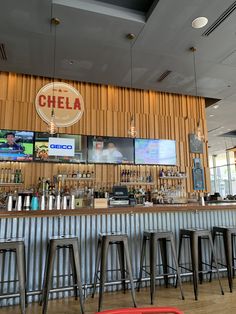 a bar with stools and television screens on the wall