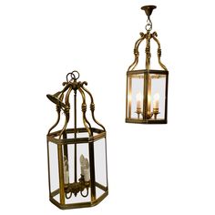 two hanging lanterns with candles in them on a white background, one is gold and the other is clear