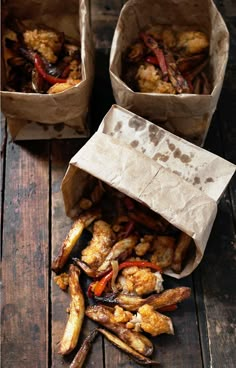 two brown paper bags filled with food on top of a wooden table