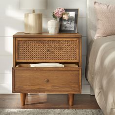 a nightstand with a wicker drawer next to a bed