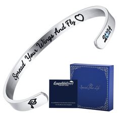 a silver bracelet with an inscription on it next to a blue box and note card