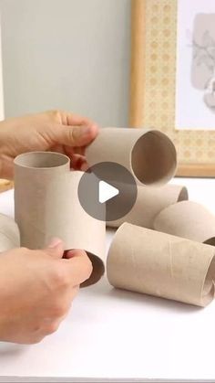 two hands holding rolled up toilet paper on top of a white table next to another hand