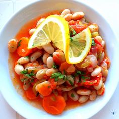 a white bowl filled with beans, carrots and lemon