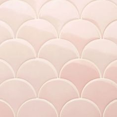 a close up view of a pink and white tile wall with circles on the surface