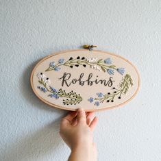 someone holding up a cross stitch sign with the word robin's in floral designs