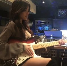 a woman sitting in front of a computer playing guitar