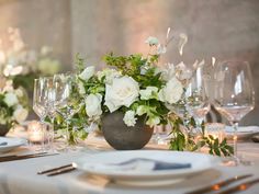 the table is set with white flowers and silver place settings for an elegant dinner party