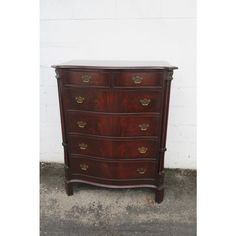 an antique chest of drawers with brass hardware on the top and bottom, against a white brick wall