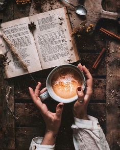 a person holding a cup of coffee in front of an open book