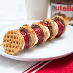 some waffles are on a white plate next to a glass of milk and strawberries