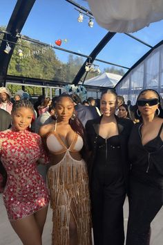 four women posing for the camera in front of a group of people at an event